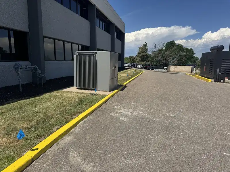Blue flags marking a water line along a commercial building's lawn and curb